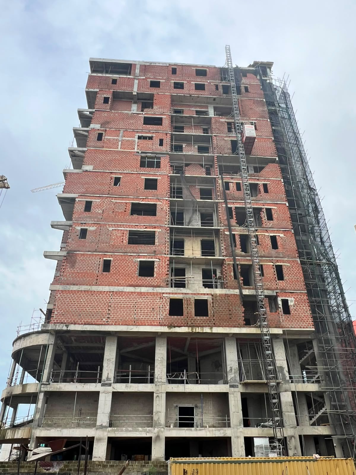 Tower under construction with red brick facade and scaffolding